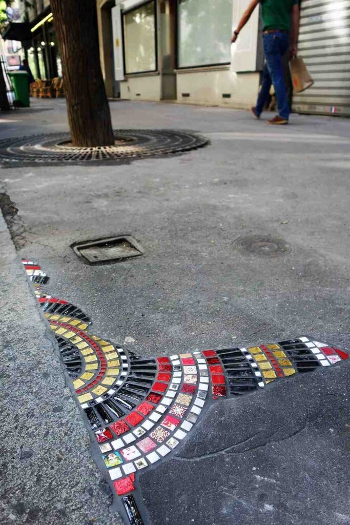 Wide view of an Ememem sidewalk mosaic repair integrated into the urban pavement