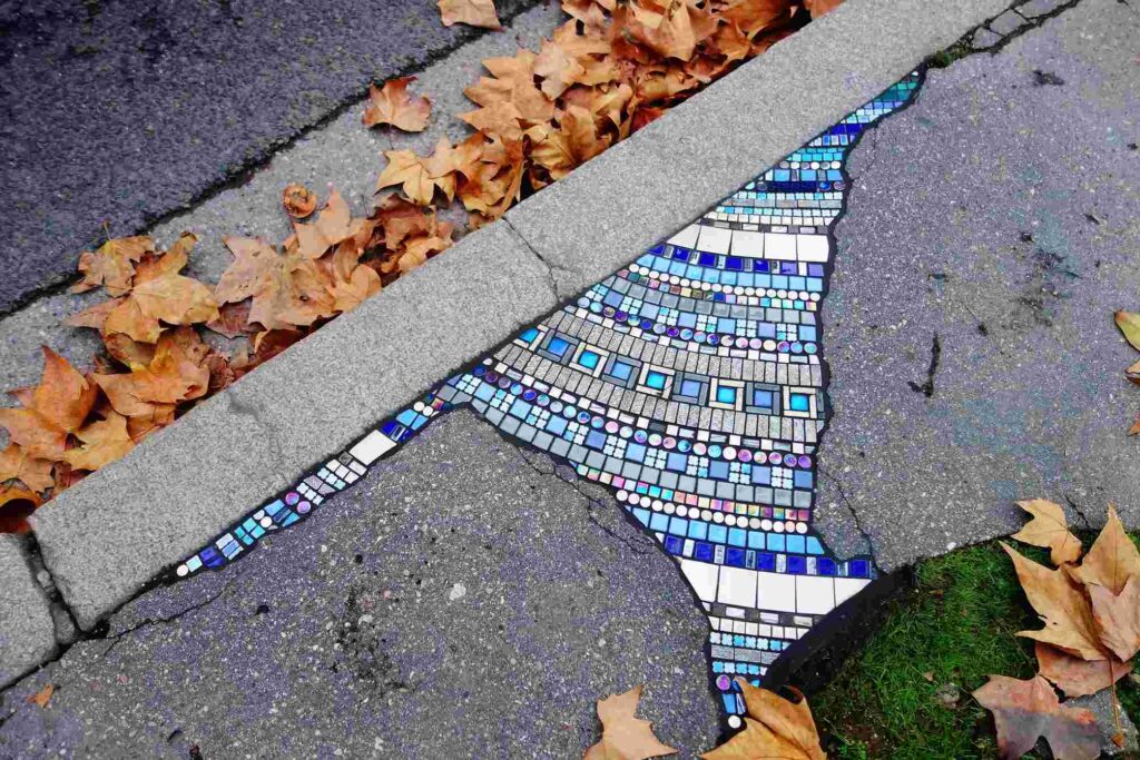 Public pavement “wound” repaired with reclaimed ceramic pieces in Ememem’s style