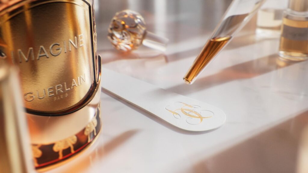 Close-up of Guerlain fragrance bottle, glass pipette and white scent strip on glossy tabletop