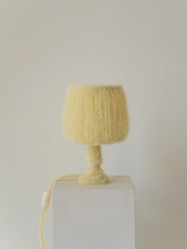 Furry knitted table lamp by napalosa_ switched off on a white pedestal