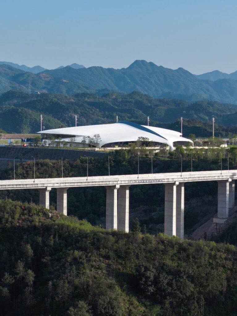 Distant view of terminal integrated into mountainous terrain with viaduct in foreground