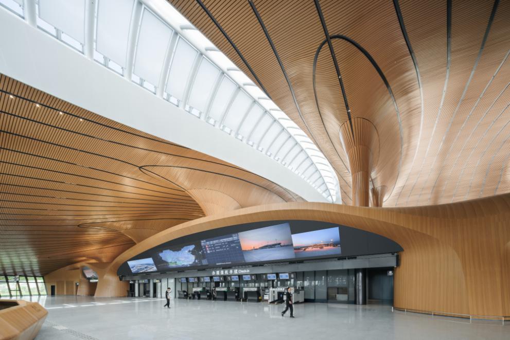 Interior terminal hall with umbrella-shaped columns and wood-toned ceiling grilles at Lishui Airport
