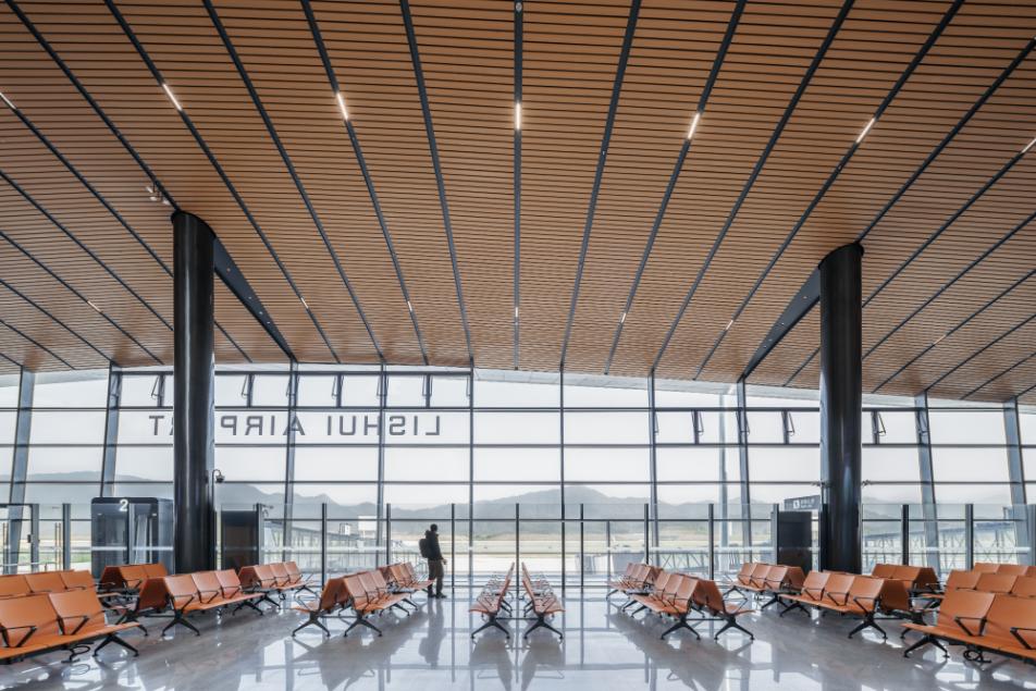 Waiting area at Lishui Airport with orange seating and full-height glazing facing the runway and mountains