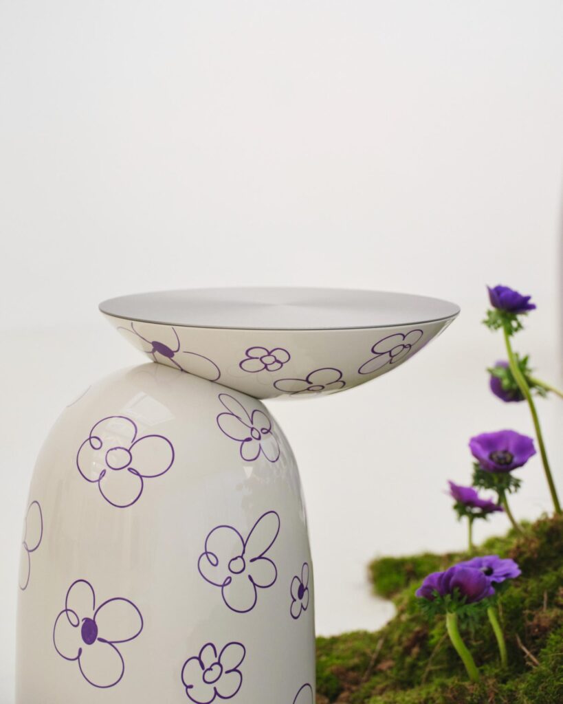 Close-up of the white side table with purple floral drawings beside the planted installation