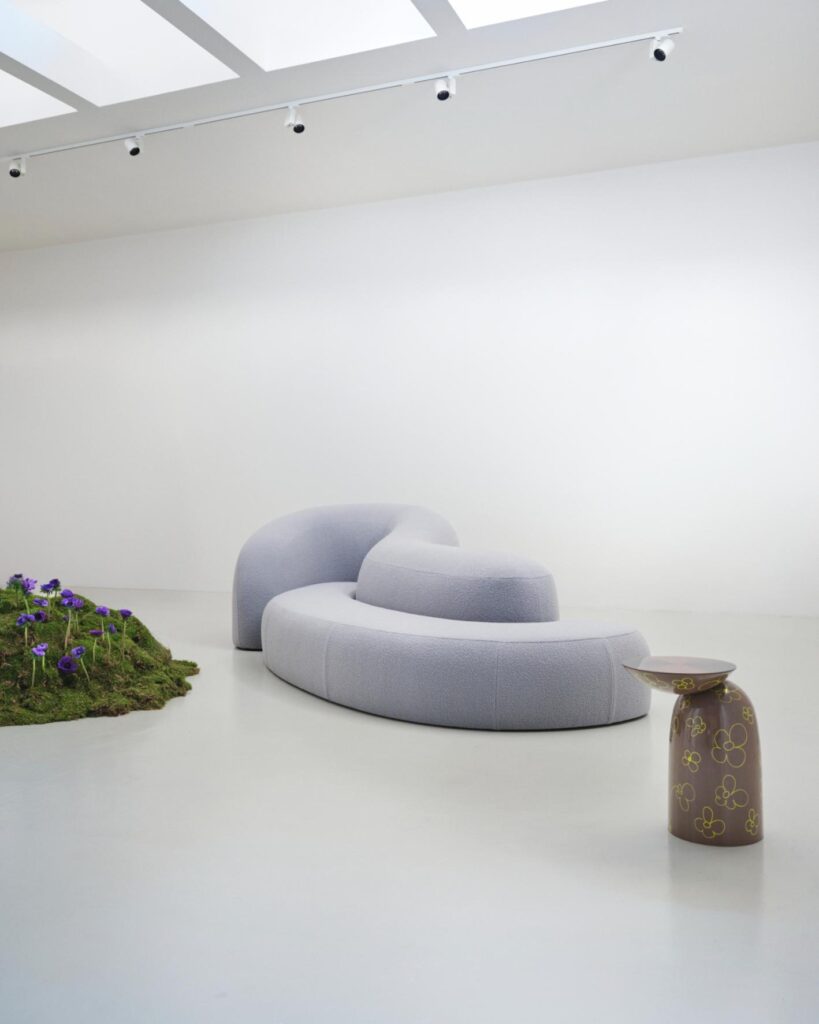 Curved modular sofa in pale upholstery with a floral-decorated side table in the foreground