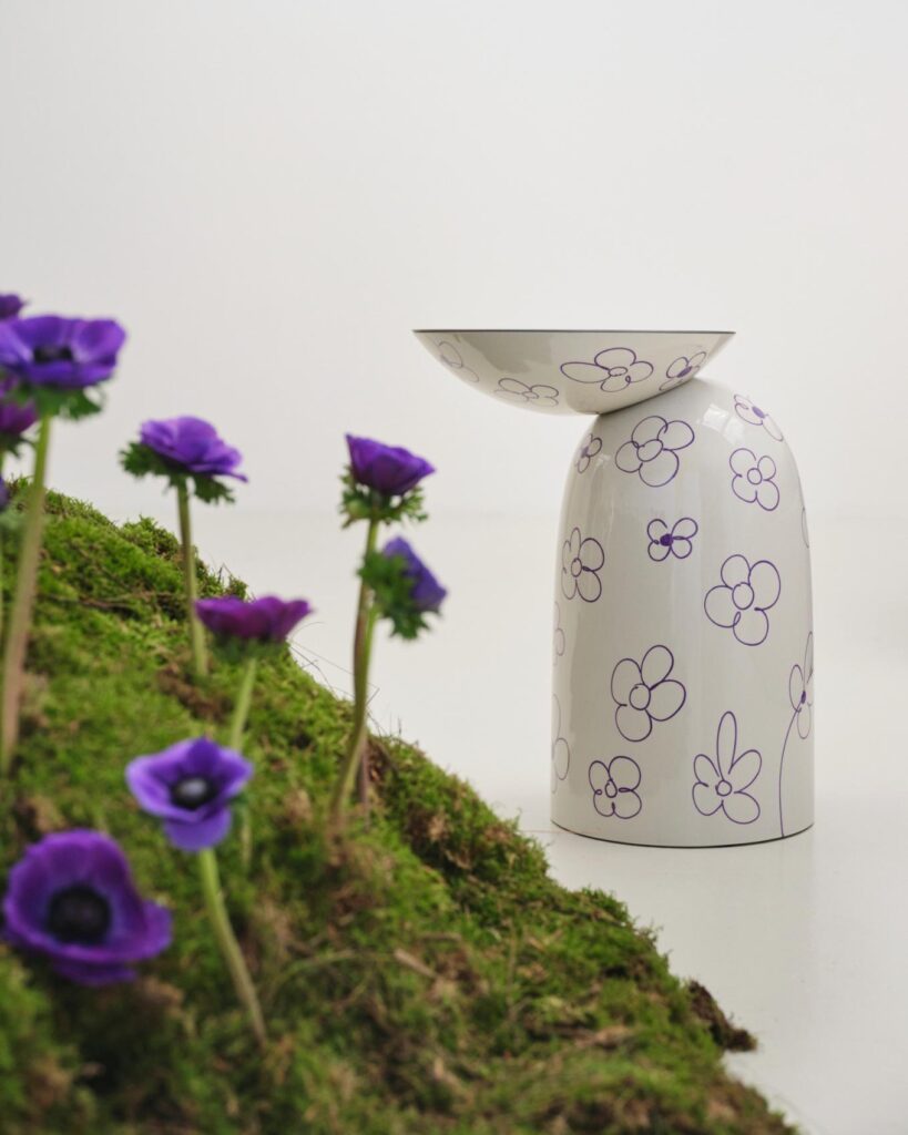 White side table with purple floral line drawings placed next to the moss mound