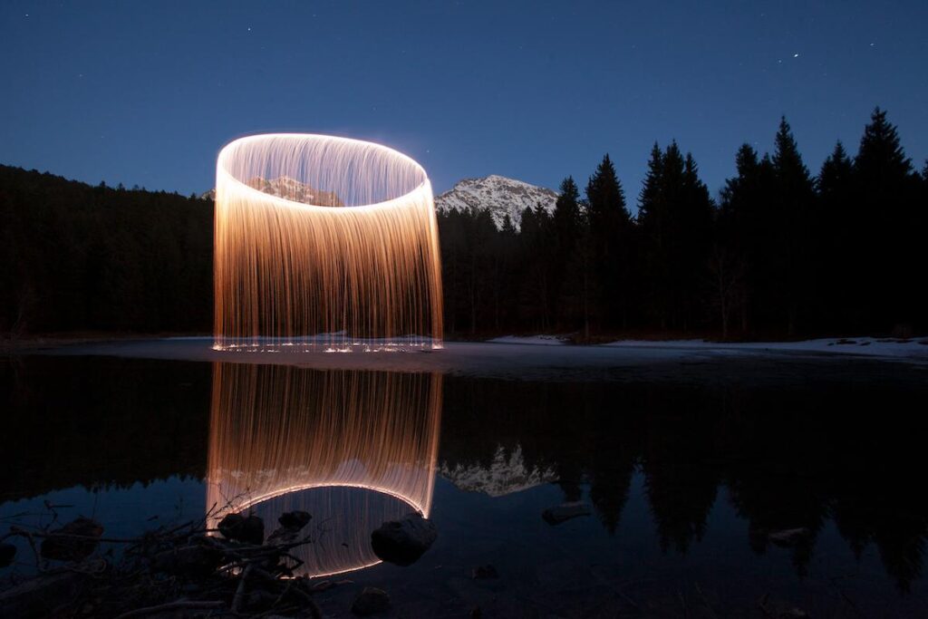 Long exposure photograph of luminous bursts above alpine mountains at night