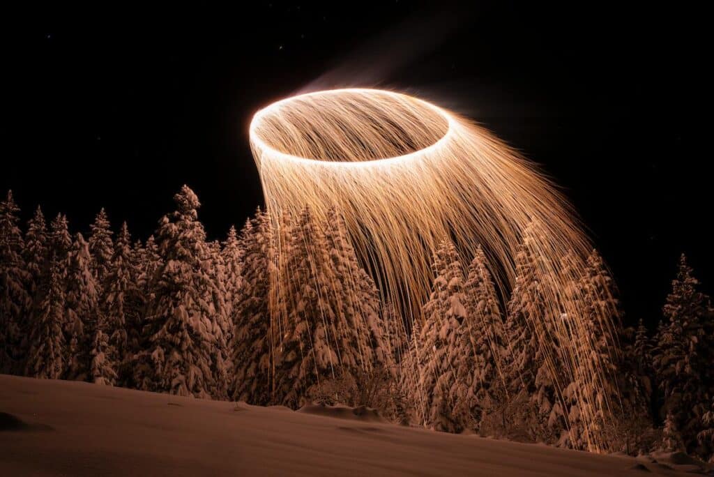 Drone generated light trails descending toward snowy terrain