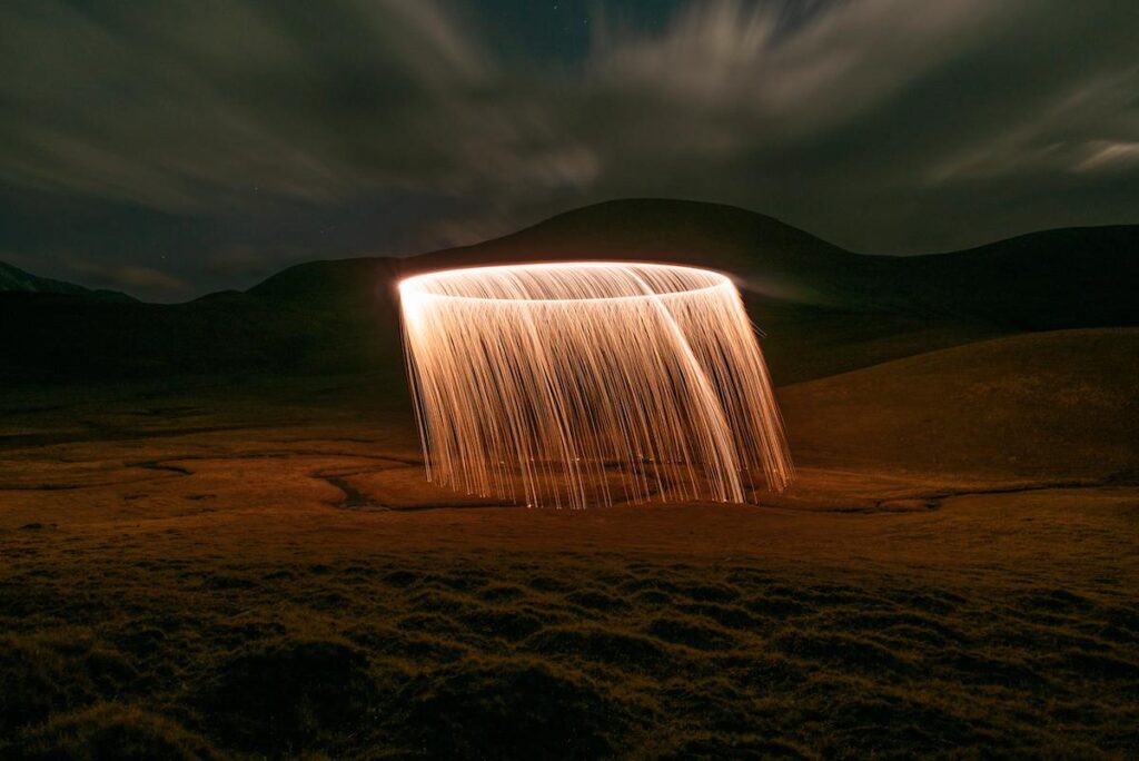 Night landscape punctuated by falling glowing particles