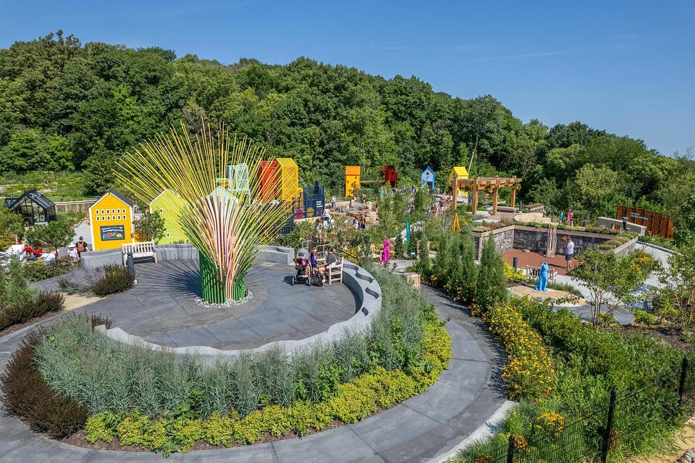 Wide view of Chorus Ventus kinetic field sculpture overlooking Lauritzen Gardens landscape