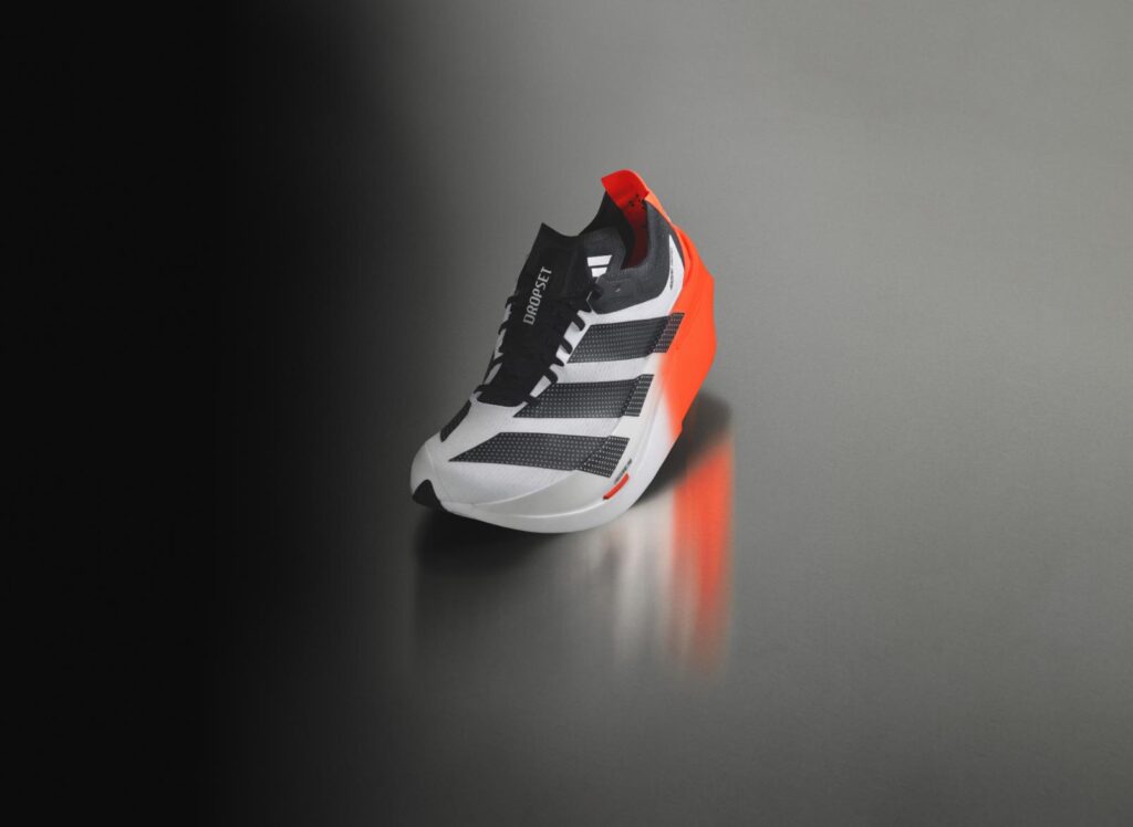 adidas Adizero Dropset Elite hybrid racing shoe on reflective surface with orange heel wedge