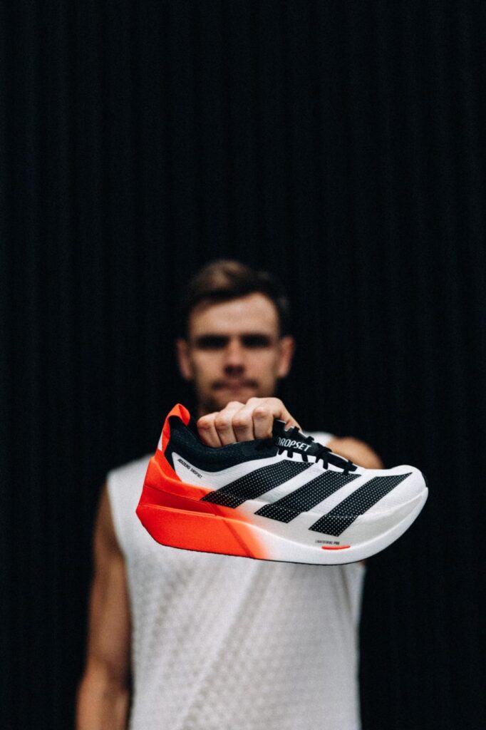 Athlete holds adidas Adizero Dropset Elite towards the camera, highlighting the sidewall and heel structure