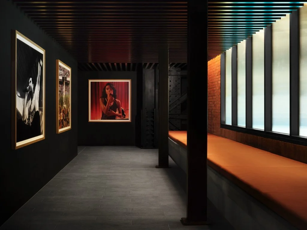 Corridor lined with music photography, integrated seating and illuminated ceiling panels