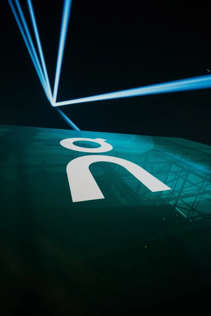 White On sportswear logo displayed on a green structure beneath blue event spotlights in Shenzhen
