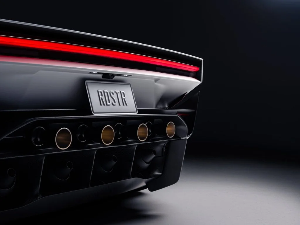 Close-up of the Tesla Roadster rear showing a continuous red LED taillight, integrated propulsion nozzles and aerodynamic diffuser.